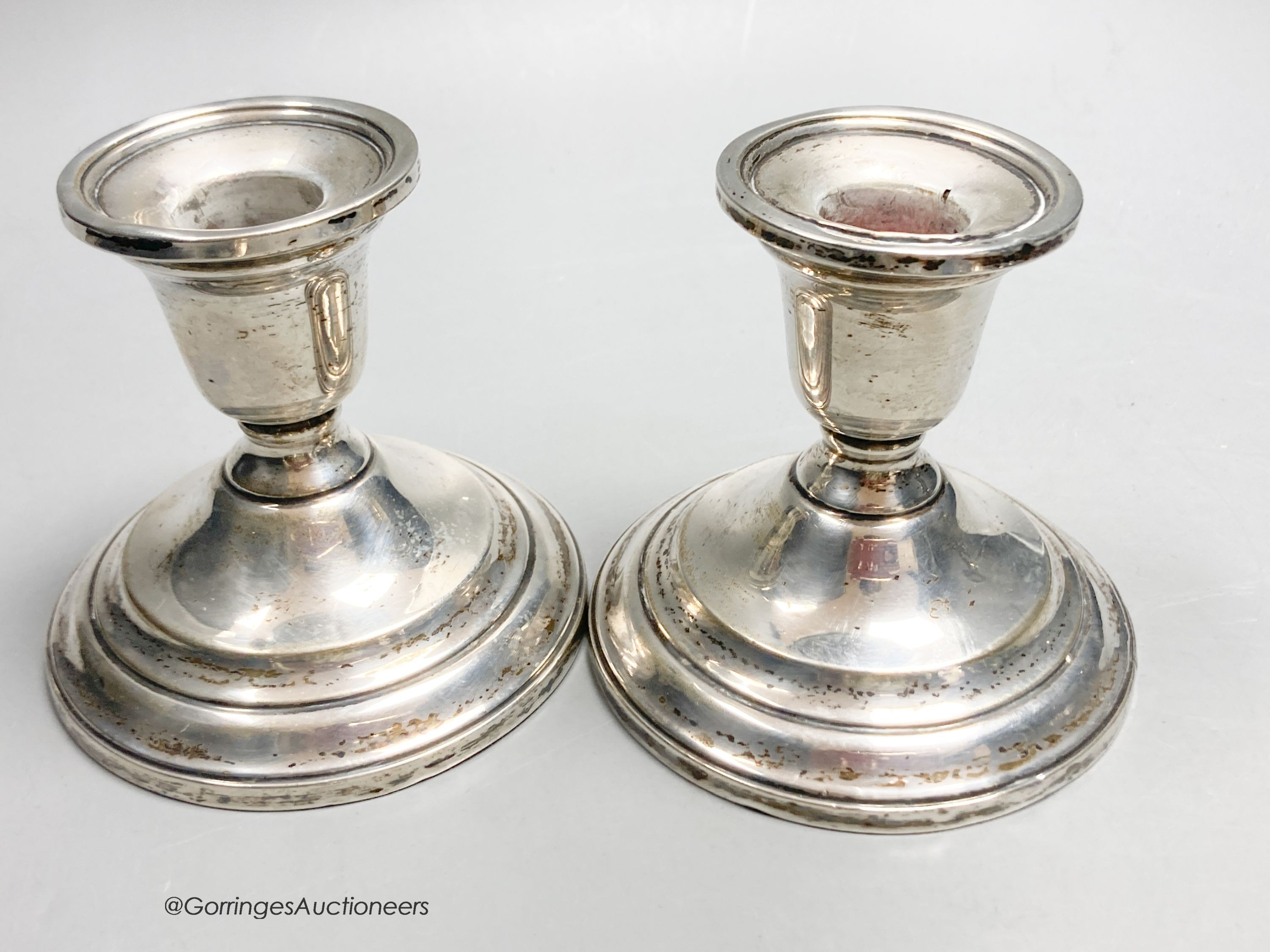 An American sterling three-branch candelabrum, 9.5oz and two pairs of similar dwarf candlesticks, 88mm, weighted.